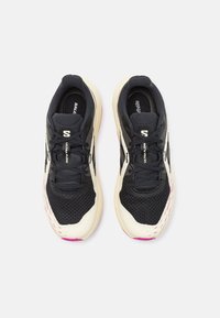 Par av svarta och vita Salomon Ultra Flow löparskor med dämpade sulor och ventilerande mesh, sedda uppifrån på vit bakgrund.