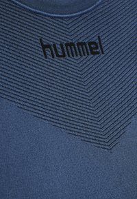 T-shirt de sport bleu marine avec un motif rayé texturé, arborant un logo "hummel" noir en haut et un col rond.