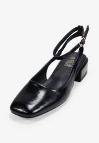 Chaussure à talon slingback en cuir verni noir avec un bout carré, une sangle fine à la cheville et un petit talon bloc. Présente un détail de boucle en ton doré.