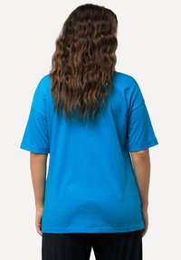 Camiseta de algodón azul con un corte relajado, mangas cortas y cuello redondo. Textura suave y puños de manga doblados.