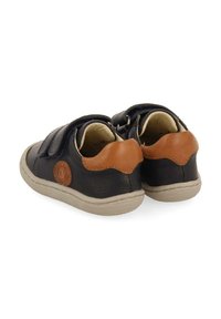 Zapatillas de cuero en azul marino con acentos marrones, que presentan una superficie texturizada, cintas de Velcro y un logo circular en el lateral.