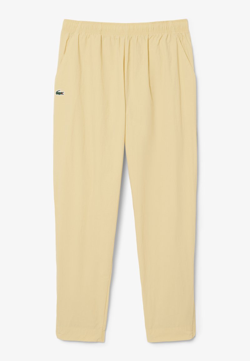 Beige casual broek met elastische tailleband, zijzakken en een klein groen krokodillenlogo op de linker dij.