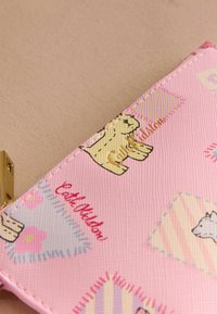 Rozā rakstaina maku, kas izgatavots no strukturēta materiāla, ar dzīvnieku un ziedu ilustrācijām, akcentēts ar zelta tekstu un aizdari.