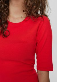 Top a costine rosso con scollatura rotonda e maniche a lunghezza gomito, caratterizzato da una silhouette aderente e una texture liscia.