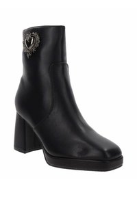 Stivale alla caviglia in pelle nera con tacco spesso, caratterizzato da un decorativo dettaglio a forma di cuore in argento sul lato e un design elegante e slanciato.