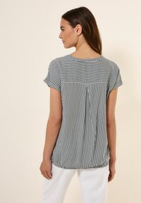 Blusa a maniche corte a righe in bianco e nero, con vestibilità comoda, scollo rotondo e dettaglio di pieghe sul retro. Tessuto morbido.