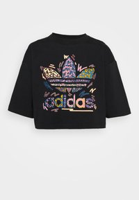 Black cropped t-shirt featuring a multicolored graphic of the Adidas logo and stylized leaves in vibrant patterns. Short sleeves, relaxed fit.