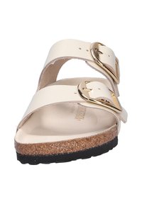 Sandal bianca con due ampie cinghie e fibbie dorate, dotata di un plantare in sughero e di una suola in gomma nera con texture.
