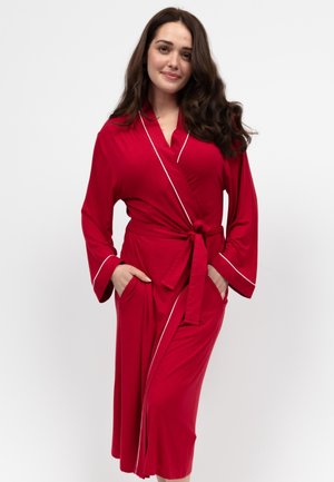 Robe rouge, de longueur genou, fabriquée en tissu doux avec de longues manches, une taille ceinturée, des poches latérales et un passepoil blanc le long des bords.
