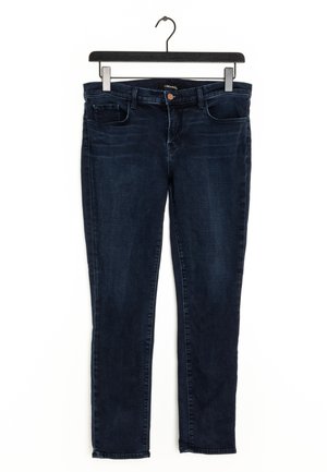 Unos pantalones de mezclilla azul oscuro cuelgan de una percha negra, con un diseño clásico de cinco bolsillos y un corte recto.