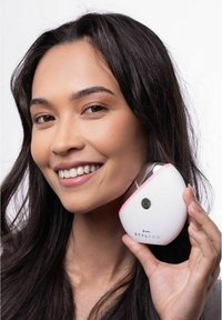 Stylpro-Gerät, das in der Hand gehalten wird, mit einem glatten weißen Gehäuse und einem rosa Akzent, kreisförmiger Form und einem Power-Button auf der Vorderseite.