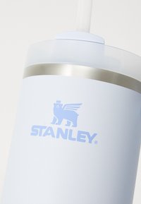 Light blue stainless steel tumbler with a smooth matte finish, silver band, and a lid with a straw. Features the Stanley logo in blue.