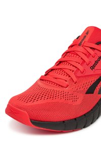 Scarpa da corsa rossa in mesh con superficie testurizzata, dettagli neri e collare imbottito. Presenta lacci piatti e un design della suola flessibile.