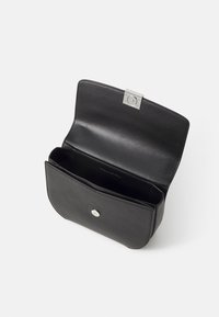 Borsa a mano nera in pelle con un design elegante, dotata di una chiusura in metallo argentato e un interno aperto con un unico scomparto.