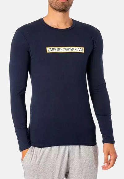 Maglietta a maniche lunghe navy in misto cotone con un design aderente. Presenta un logo "Emporio Armani" oro e bianco sul fronte.