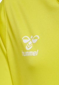Felle gele sporttrui van gladde stof, met een wit logo van een gestileerde bij en de merknaam "hummel" eronder.