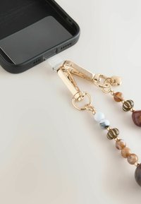 Husă de telefon neagră cu un accesoriu metalic aurit. Include un șir de mărgele multicolore: maro, albastru și translucid, cu un charm în formă de inimă.