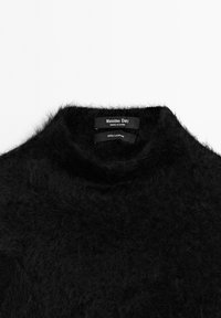 Svart fluffig kashmirtröja med krage, med "Massimo Dutti" varumärkesetikett och "100 % kashmir" märkning inuti.