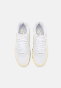 Vita sportskor med en design med gula accenter, som har texturerad mesh och släta lädermaterial, rund tå och platta snören.