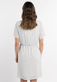 Robe bleu clair avec un petit motif floral rose, manches courtes, taille élastique, longueur genou et texture de tissu douce.