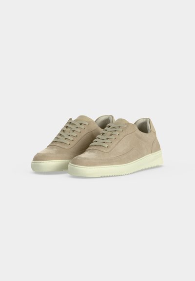 Μπεζ σουέντ αθλητικά παπούτσια χαμηλού ύψους με κλείσιμο με κορδόνια και λευκές λαστιχένιες σόλες σε απλό ανοιχτό γκρι φόντο.
