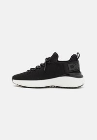 Scarpa sportiva nera con tomaia in mesh testurizzato, lacci elastici e suola bianca. Presenta un accento nero sul tallone con il logo.