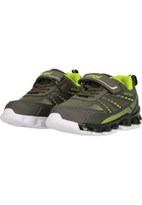 Chaussures de sport en matériau softshell, avec un dessus vert foncé, des accents réfléchissants et une semelle blanche avec des points de traction noirs.
