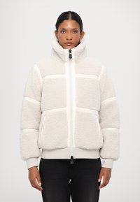Kermitehtävä fleece-takki, jossa on korkea kaulus, vetoketjukiinnitys ja vaakasuuntainen raidallinen muotoilu. Varustettu etutaskuilla ja ribbaamalla hihansuilla.