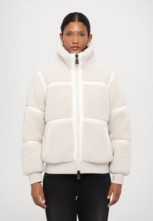 Kermitehtävä fleece-takki, jossa on korkea kaulus, vetoketjukiinnitys ja vaakasuuntainen raidallinen muotoilu. Varustettu etutaskuilla ja ribbaamalla hihansuilla.