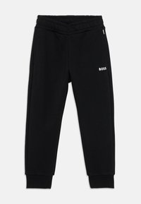 Μαύρες βαμβακερές φόρμες με ριπ waistband, φαρδιά στους γοφούς και συρρικνωμένα μπατζάκια, και ένα μικρό λευκό λογότυπο "BOSS" στην αριστερή πλευρά.