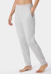 Pantaloni della tuta grigi realizzati in materiale morbido, con una vita elastica, tasche laterali e polsini aderenti. Texture liscia in tutto il capo.