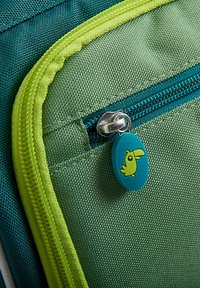 Pocchetto colorato con zip in tessuto verde e turchese, con un accento della zip di un vivace verde e un tirazip blu decorato con un disegno di un uccello giallo.
