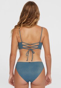 Set di bikini blu con finitura scintillante testurizzata, spalline regolabili e design con lacci sul retro. Parte inferiore a vita alta con copertura minima.