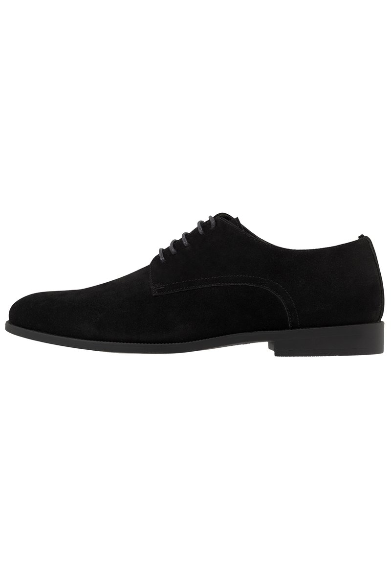 Chaussure habillée pour homme en suede noir à lacets, avec un talon bas et un design épuré et minimaliste, présentée de côté sur un fond blanc.