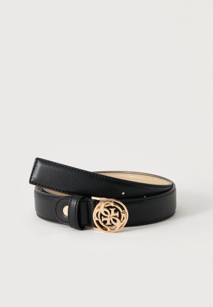 Cintura in pelle nera arrotolata con fibbia rotonda dorata con lettere intrecciate su uno sfondo chiaro uniforme.