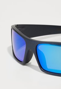 Sonnenbrille mit einem mattschwarzen Rahmen und blauen Verlaufslinsen, ausgestattet mit einem Wraparound-Design und weichen Nasenpolstern für mehr Komfort.