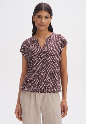 Korte mouwen, diep burgundy top met een gestructureerd, wit abstract patroon; heeft een v-halslijn en een ontspannen pasvorm. Gecombineerd met lichte linnen broek.