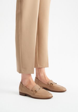 Beige leren instappers met een licht puntige neus, banddetail met metallic accenten, en een lage gestapelde hak.