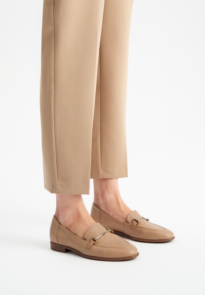 Beige nahka loaferit, joissa on hieman terävät varpaat, hihnatiedot metallisilla yksityiskohdilla ja matala pinottu korko.