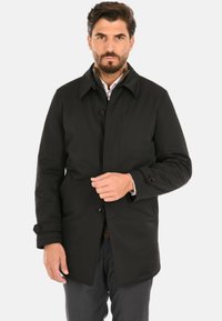 Cappotto nero dal design dritto, chiusura con bottoni e ampio colletto. Realizzato in tessuto liscio, presenta tasche laterali e polsini regolabili.