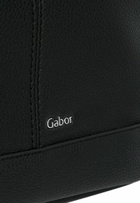 Borsa a tracolla in pelle nera con superficie texturizzata, cuciture sottili e accento del logo "Gabor" in argento sul lato inferiore destro.