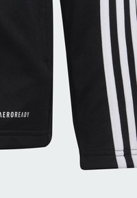 Pantalones cortos deportivos negros con tres rayas verticales blancas en el costado. Hechos de un tejido ligero, presentan el logo "AEROREADY" cerca del dobladillo.