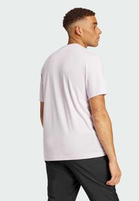 Světle fialové bavlněné tričko s krátkým rukávem a volným střihem, doplněné tmavými kalhotami. Hladká textilie, jednoduchý design, bez grafiky.