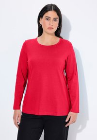 Rotes Baumwolloberteil mit langen Ärmeln, rundem Ausschnitt, glatter Textur und lockerer Passform. Geeignet für den Freizeitlook oder zum Layering.