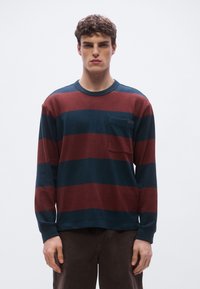 Μπλούζα με μακριά μανίκια και ρίγες σε σκούρο μπλε και μπορντό, με στρογγυλή λαιμόκοψη, τσέπη στο μπροστινό μέρος και απαλό ύφασμα.