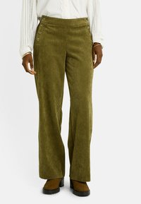 Pantalones de pana verde oliva con piernas anchas, que cuentan con canalones verticales y grandes botones decorativos en la cintura. Tejido suave y texturizado.