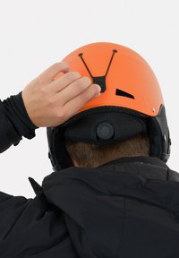 Orange hjelm med sorte accenter, med en glat yderside, ventilationsåbninger, justerbart pasformssystem og tekstureret indvendig polstring.