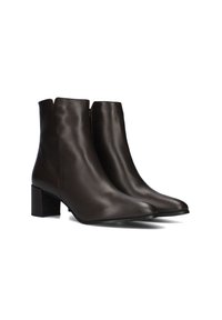 Een paar donkerbruine leren enkelboots met blokhakken en ritsen aan de zijkant, gepresenteerd op een witte achtergrond.