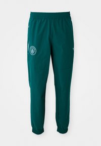 Pantaloni sportivi turchesi con vita elastica. Presentano un logo del Manchester City e polsini elastici alle caviglie. Materiale in poliestere.