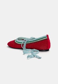 Röd virkade ballerinas med rund tå, med ljusblå spets och gröna randade detaljer längs kragen. Texturerat material.